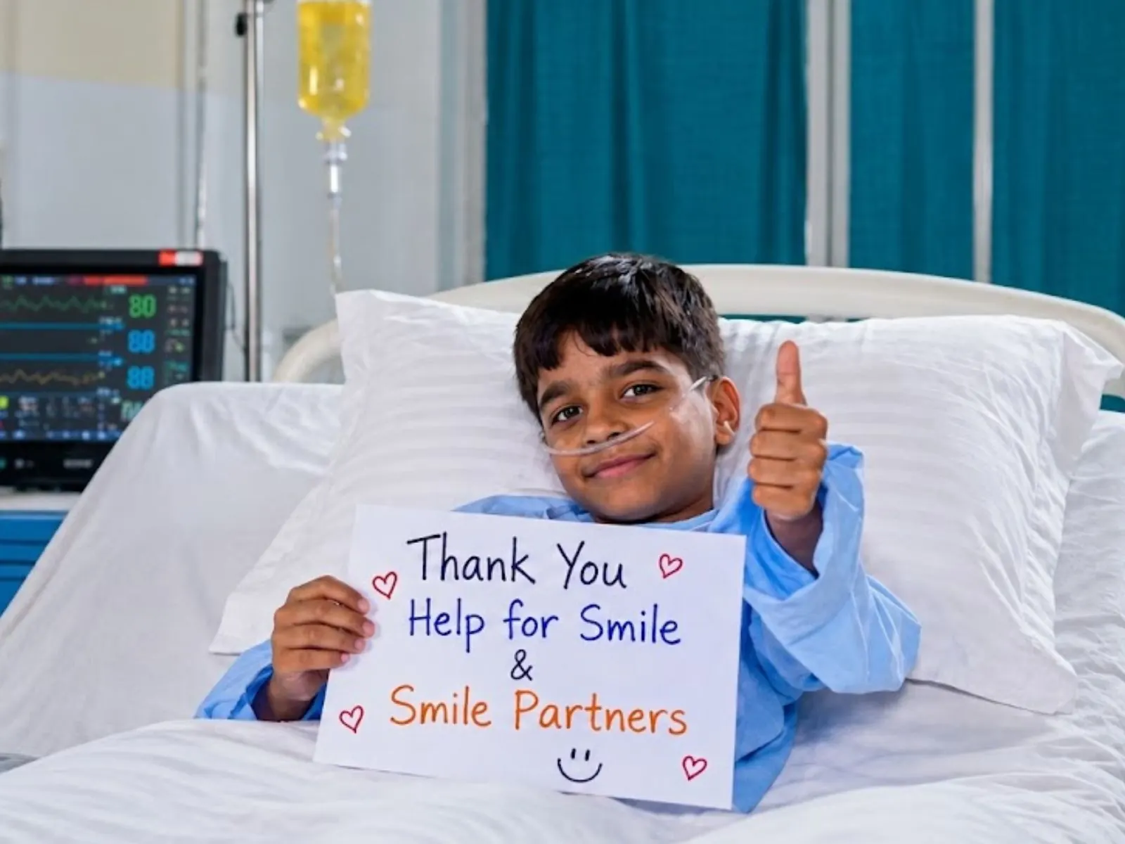 A child in hospital holding a thank-you note to Help For Smile and its Smile Partners